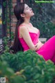 A woman in a pink dress sitting on a bench.