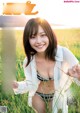 A woman in a bikini standing in a field of tall grass.