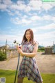 A woman in a plaid dress holding a hose.