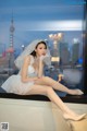 A woman in a wedding dress sitting on a window sill.