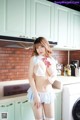 A woman in a maid outfit posing in a kitchen.