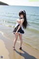 A woman in a maid outfit standing on a beach.