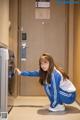 A woman kneeling down next to a washing machine.