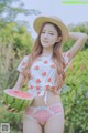 A woman in a straw hat holding a watermelon.