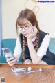 A young woman sitting at a table looking at her phone.